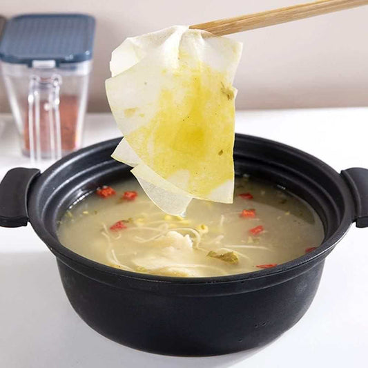 Oil absorption paper removing grease from hot soup in black bowl with chopsticks