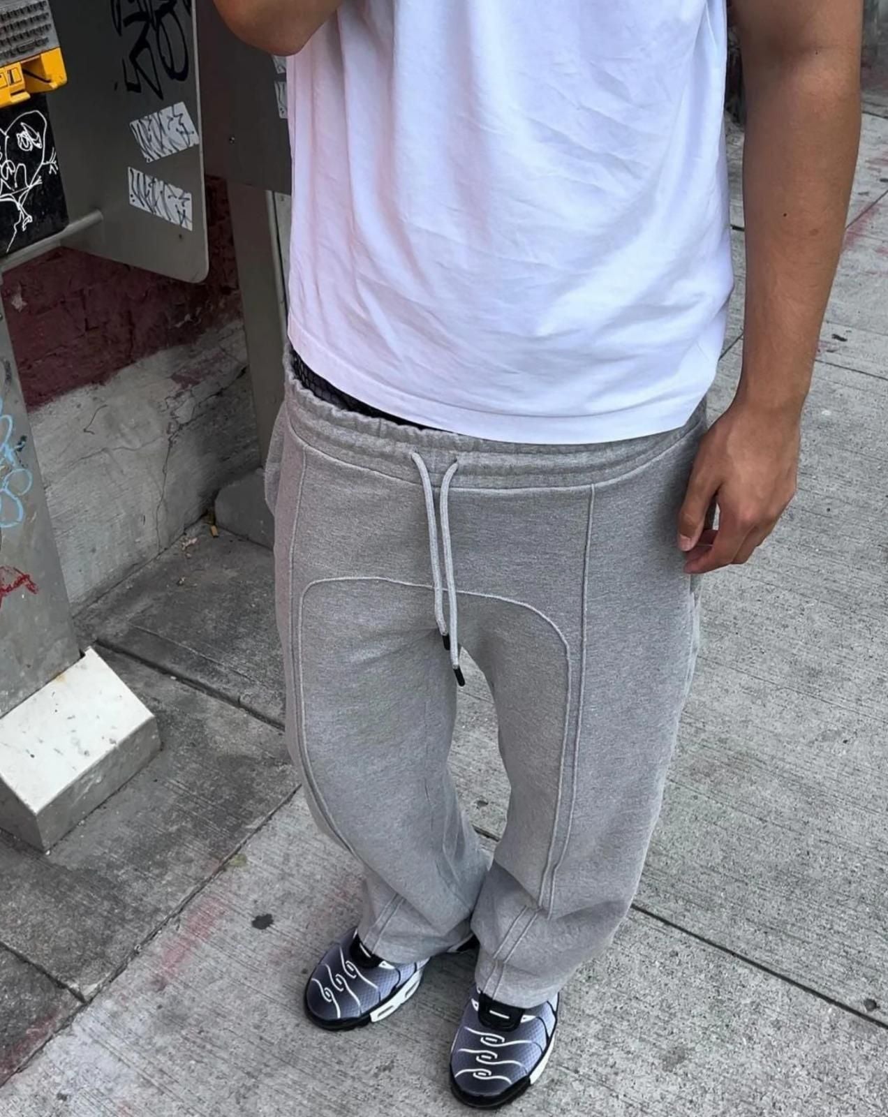 Men's elastic waist gray sweatpants with drawstring and regular fit worn with white t-shirt and sneakers on urban street