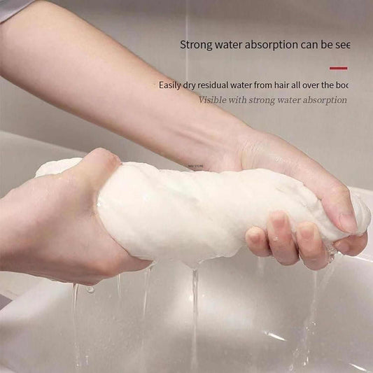 Hands squeezing a white compressed bath towel tablet with water dripping, demonstrating strong water absorption and quick drying ability.