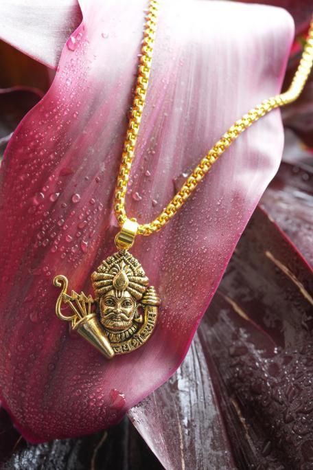 Golden Khatu Shyamji pendant with chain made of gold-plated stainless steel displayed on a pink surface